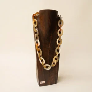 Collar de asta natural colocado sobre un expositor de madera