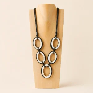 collar asta natural de color blanco y negro colocado sobre un expositor de madera