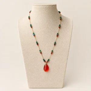 Collar exhibido en un maniquí, con piedras rojas y verdes, destacando su diseño elegante y colorido.